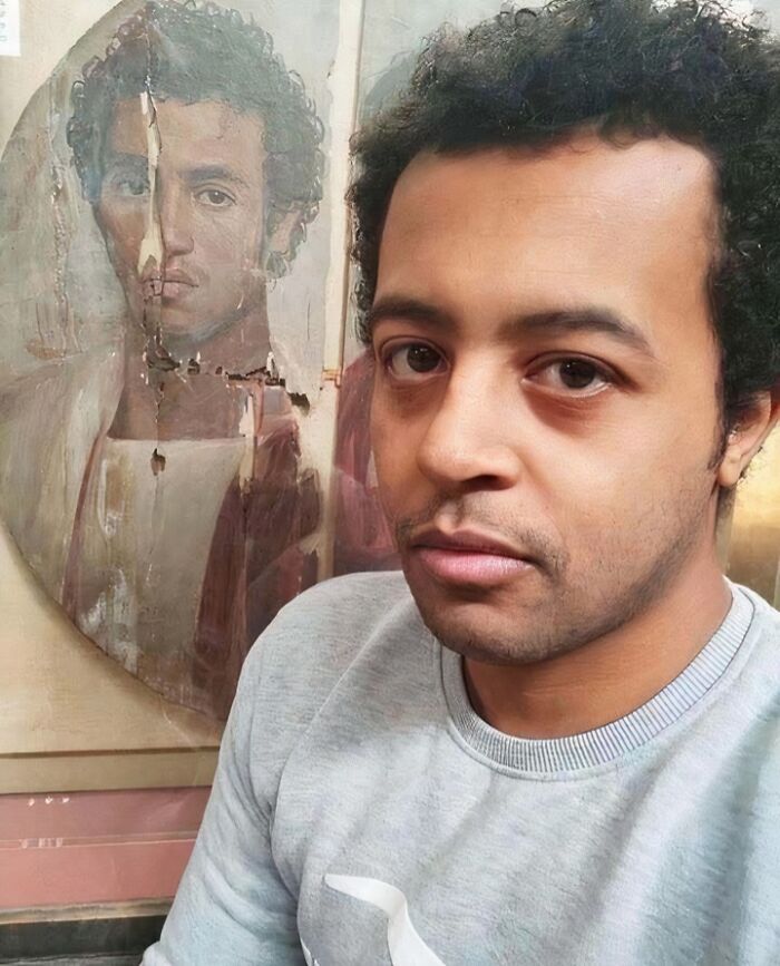 Man standing near a historical painting with a similar face, highlighting an interesting moment in history.