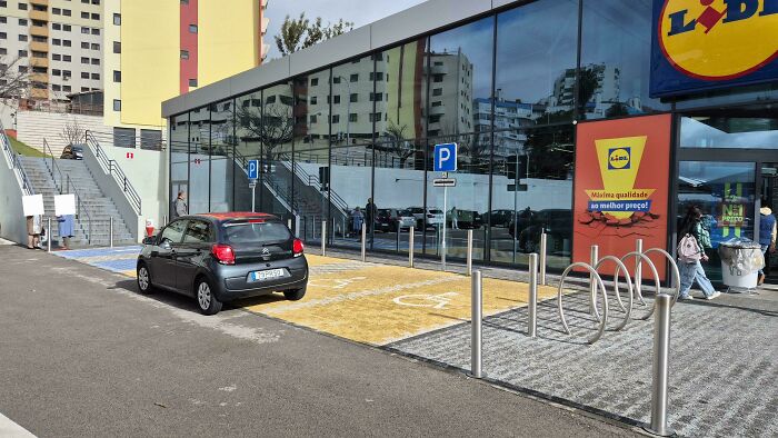 Car parked in a handicapped spot outside a supermarket, showcasing entitled behavior.