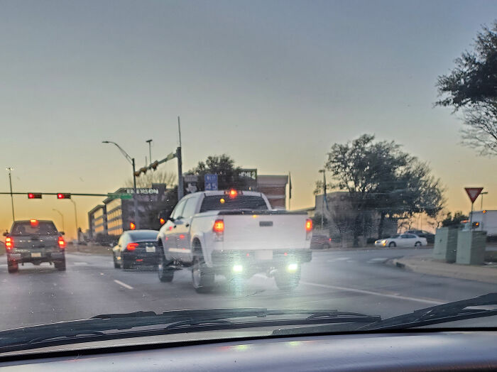Truck with bright lights in traffic at sunset, highlighting entitled driving behavior.