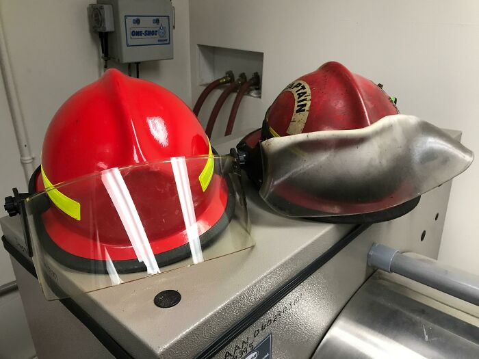 Two fire helmets on display, showing wear over time and equipment changes.