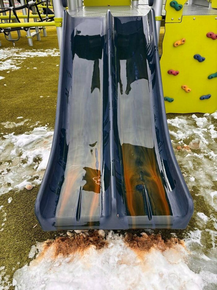 Two slide playground covered in ice and dirty water, creating an entitled and neglected appearance.