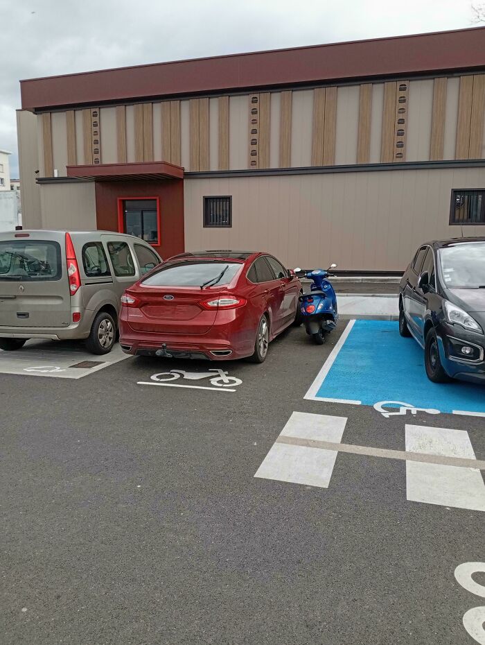 A red car and scooter parked in disabled spaces, illustrating entitled behavior.