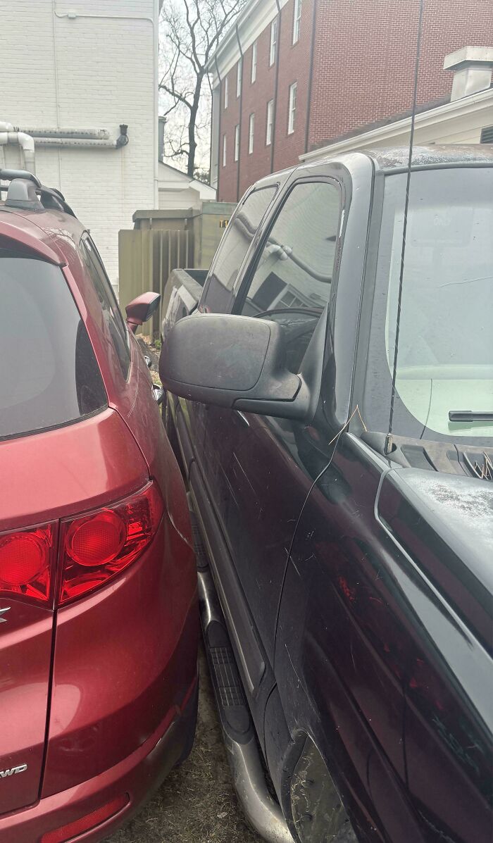 Entitled parking: a red SUV tightly parked next to an oversized black truck, leaving no space.