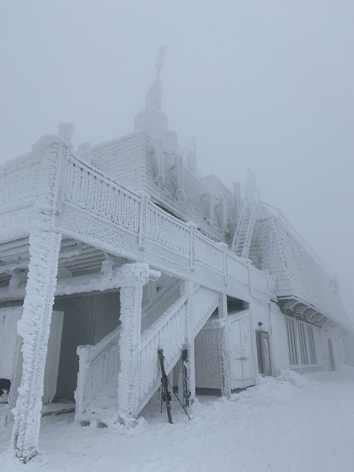 Snow-covered building and skis resting outside in extreme winter conditions unique to Canada.