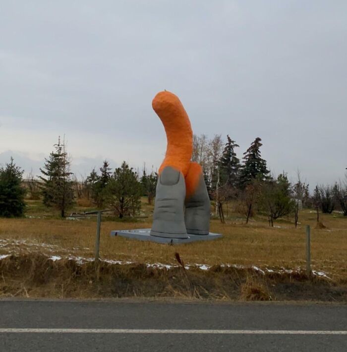 Quirky orange sculpture of a large thumb in a Canadian landscape, showcasing Just-Canada-Things.