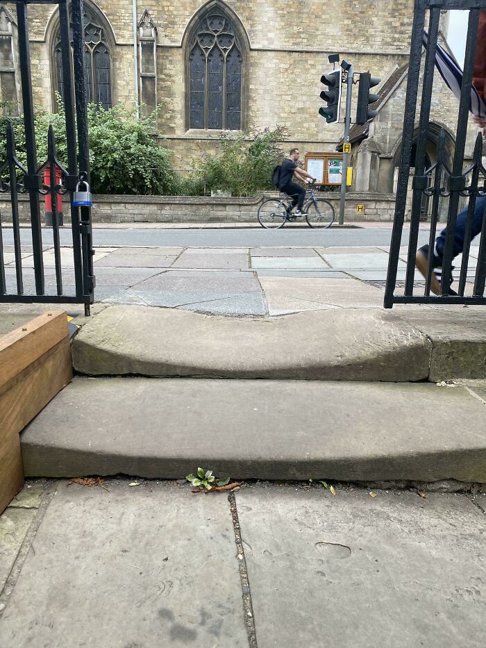 Outdoor stone steps with a view of a cyclist passing by, highlighting the contrast of time vs. things.