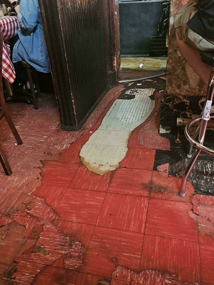 Worn-out red floor tiles and seating, showing the effects of Time-vs.-Things in a restaurant setting.