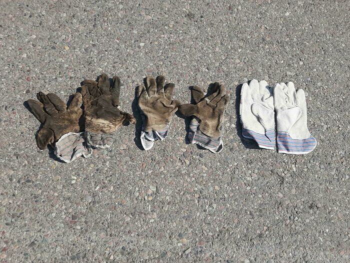 Four pairs of work gloves on concrete, showing time's impact on things through wear and tear contrast.