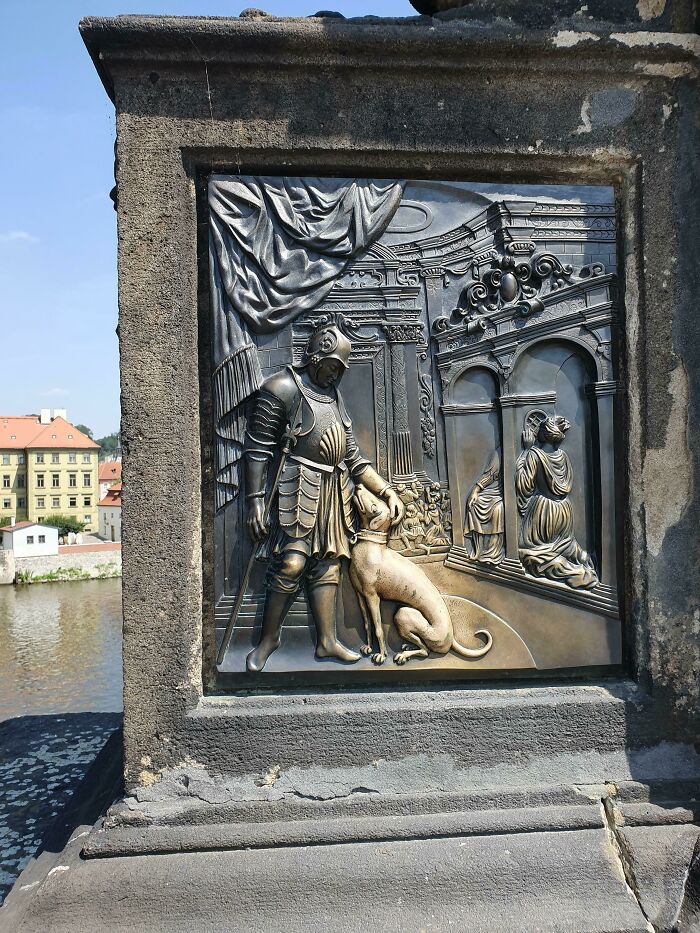 Bronze relief depicting knight and dog on a historic European bridge, emphasizing time vs. things theme.