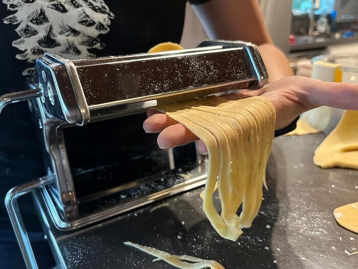 Making fresh pasta as part of a digital detox, with dough being rolled through a pasta machine in a kitchen setting.