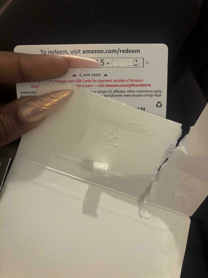 Person holding an Amazon gift card, exposing potential scam details and instructions for redeeming online.