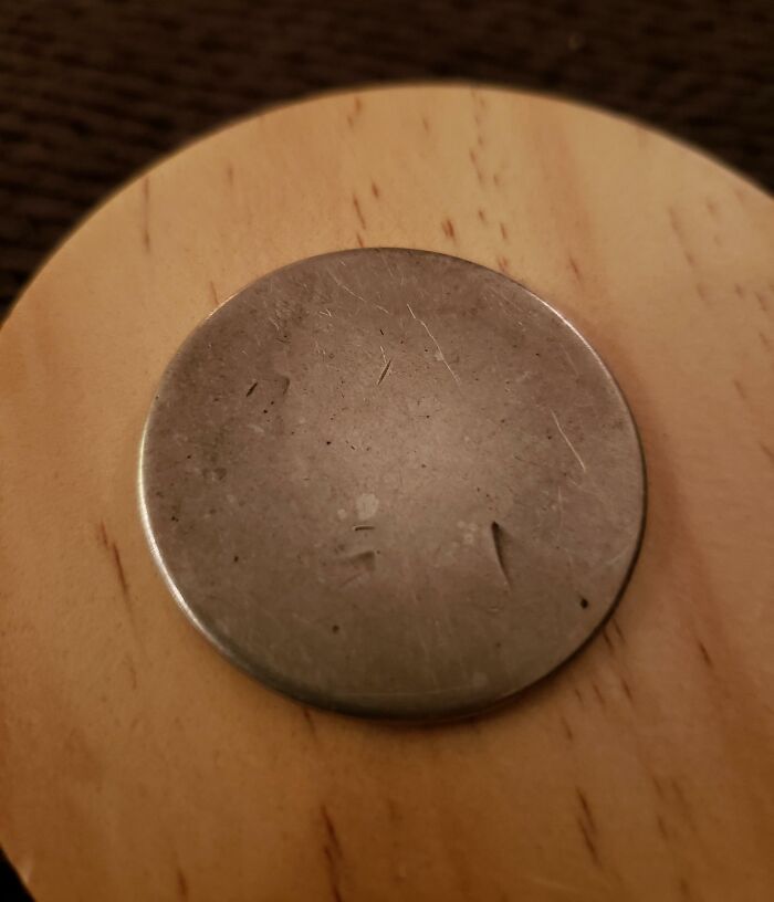 A well-worn metal disc placed on a wooden surface, representing the theme of Time versus Things.