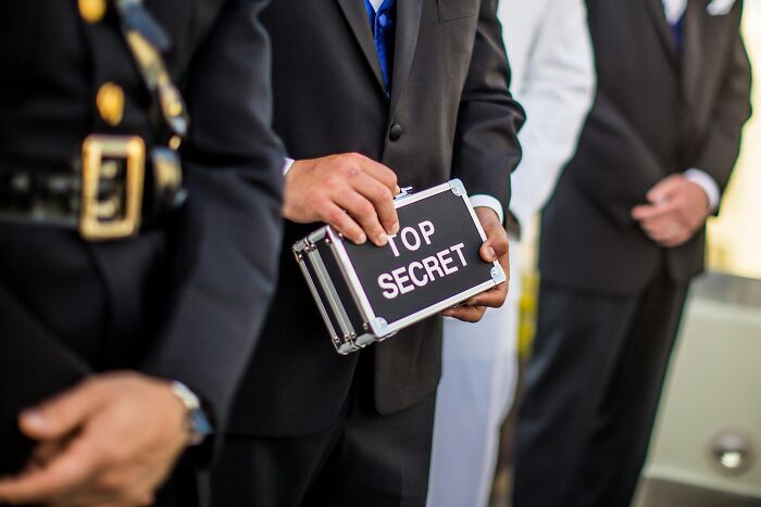 Person holding a "Top Secret" briefcase while standing in a line, symbolizing intrigue often found in Wikipedia articles.