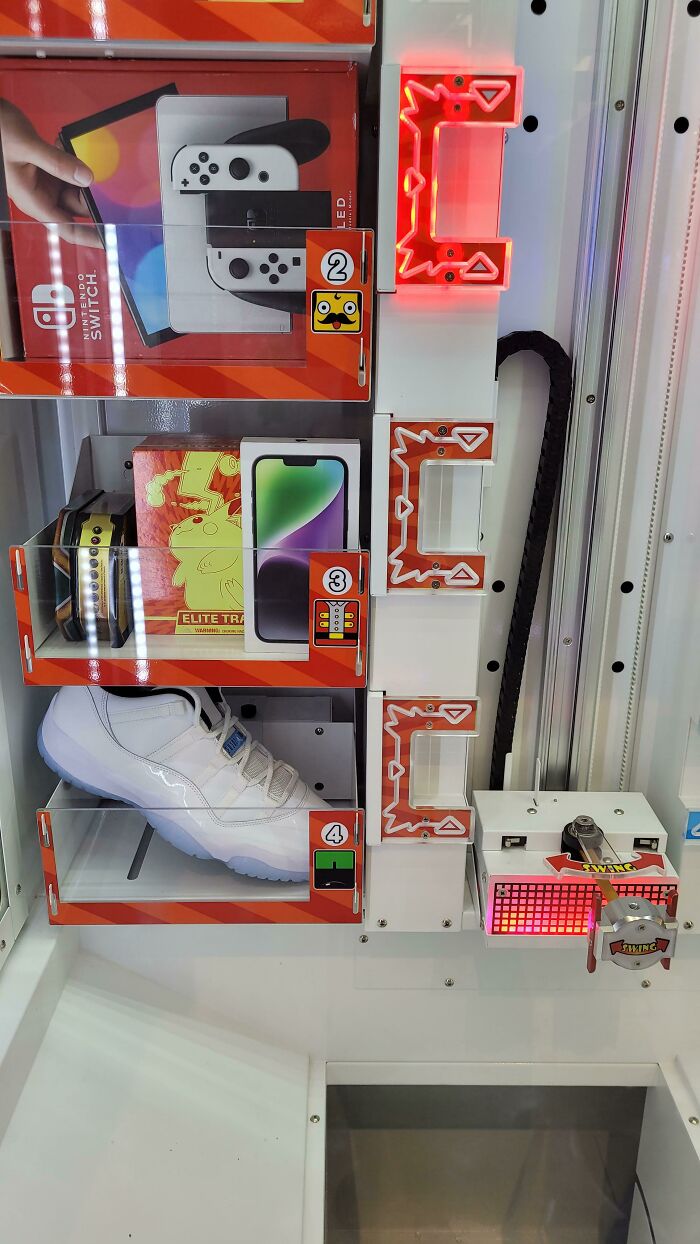 Claw machine game with various prizes like a Nintendo Switch and shoe, illustrating shameless scams and unlikely wins.