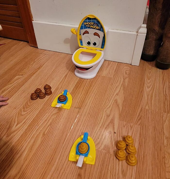 Toy toilet game on wooden floor with p**p-shaped pieces, highlighting toilet humour theme.