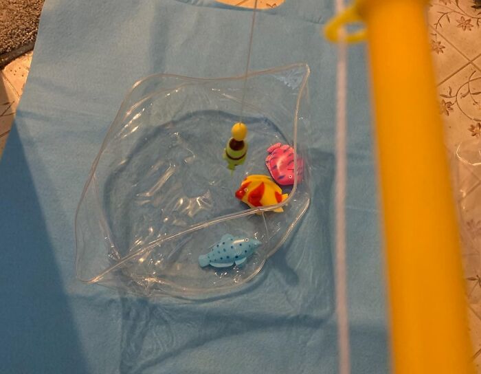 Toy fishing rod with plastic fish in a toilet-shaped bowl, creating toilet humour.