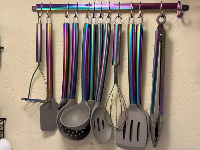 Colorful kitchen utensils with rainbow metallic handles neatly hanging, showcasing quirky gems for fun and functionality.