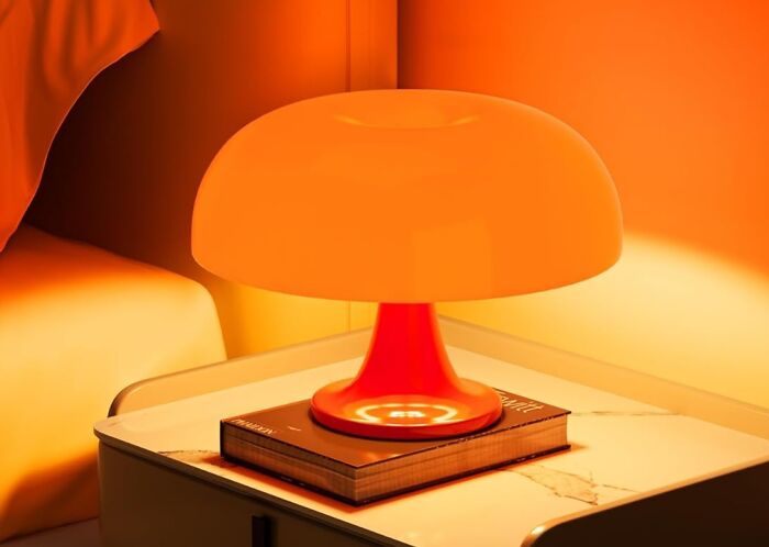 Orange modern lamp on a bedside table with a book, showcasing sneakily useful decor items for functional style.