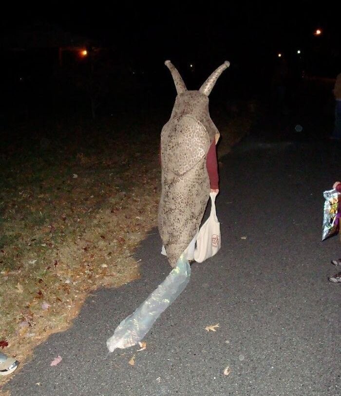 Person in a humorous slug costume, walking on a dark street.