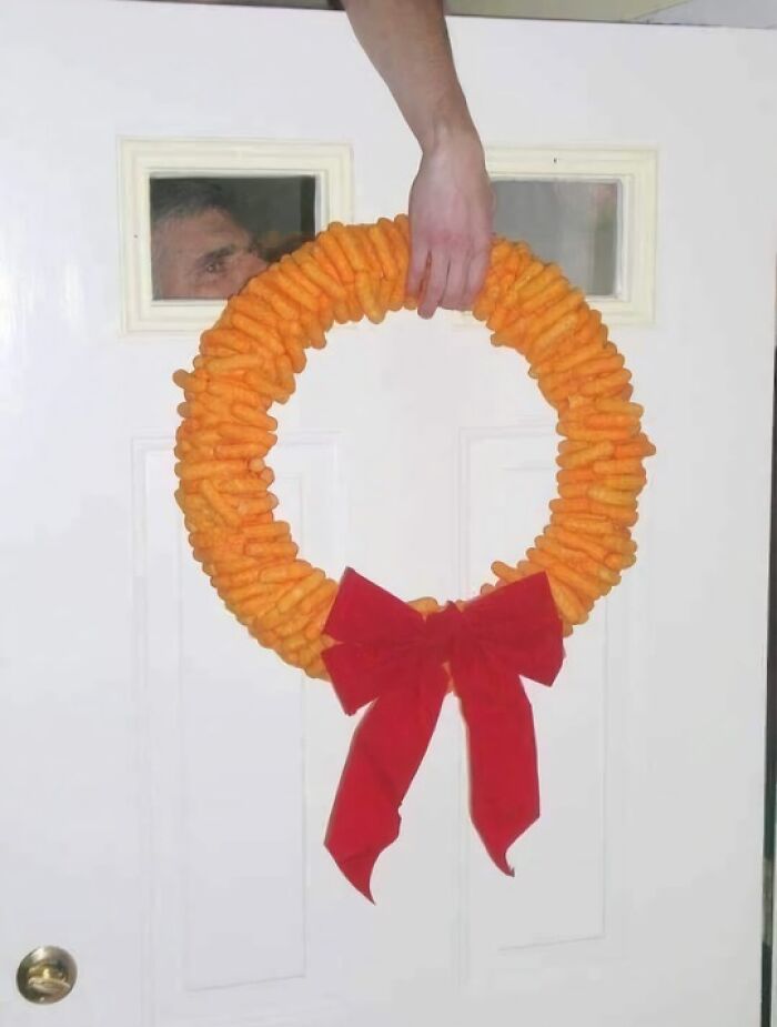 Funny random photo of a Cheetos wreath with a red bow hanging on a door.