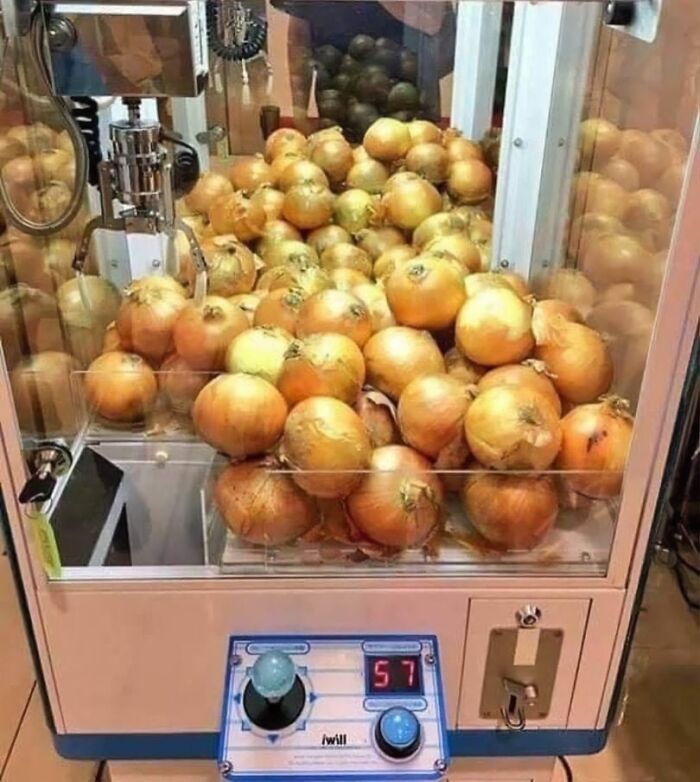 Claw machine filled with onions instead of prizes, creating a random funny scene.