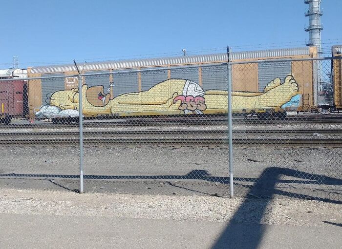 Graffiti of a cartoon character sleeping on a train car, adding humor to a random street scene.