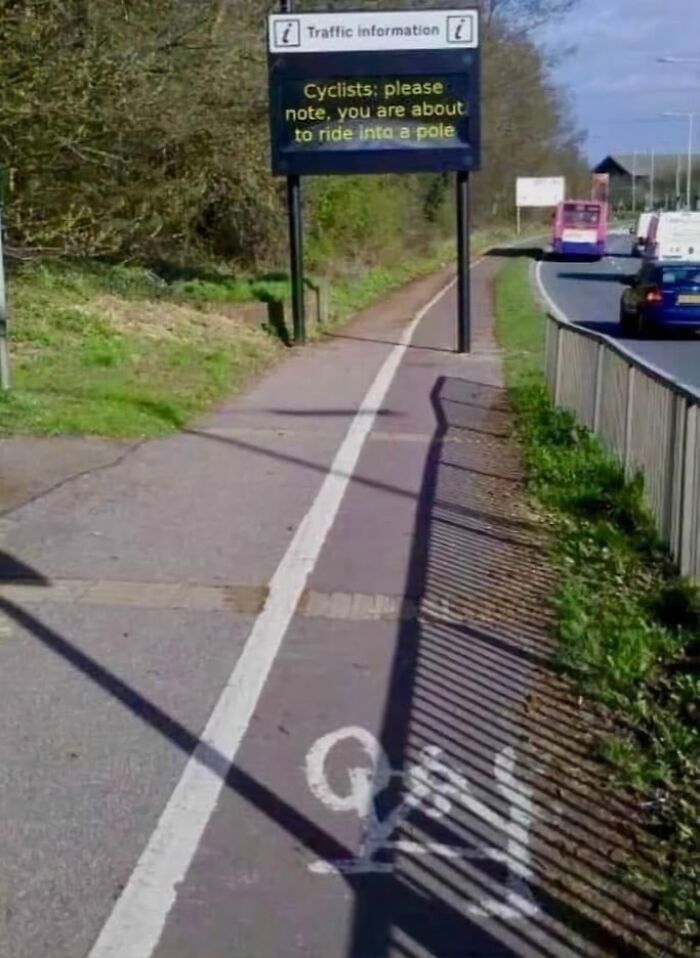 Funny random photo of a cycling path with a warning sign about a pole hazard.