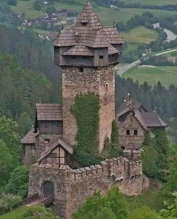 Historic castle surrounded by lush greenery, showcasing medieval architecture in a scenic landscape.