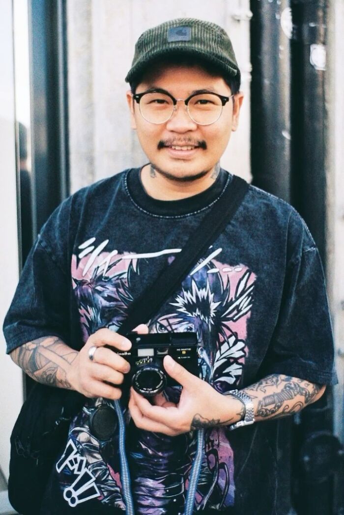 Portrait of a man wearing glasses and a cap, holding a camera. Captivating street portrait of a stranger by photographer.