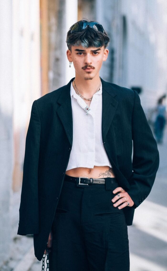 Striking stranger in street portrait, wearing a suit jacket with sunglasses on head, posing confidently.