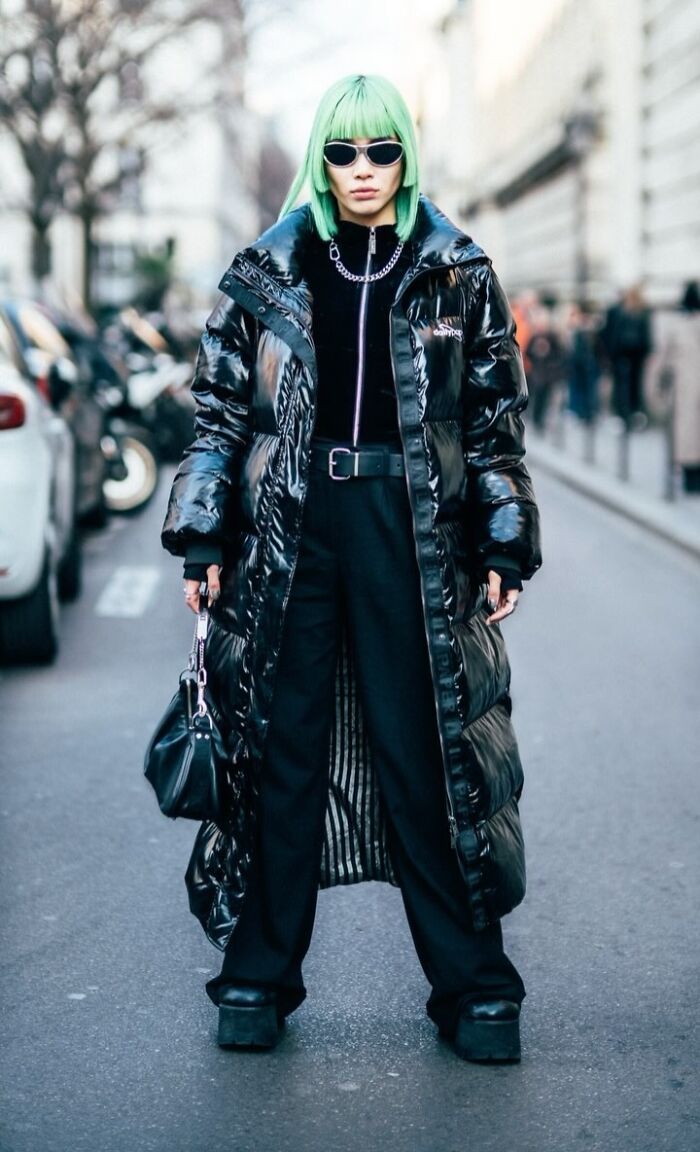Street portrait of a visually striking stranger with green hair, wearing a glossy black coat and sunglasses.