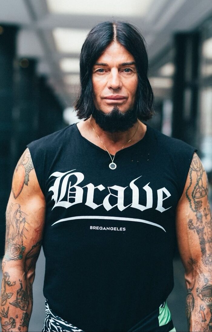 Man with tattoos and long hair in a "Brave" shirt, exemplifying visually striking street portraits.
