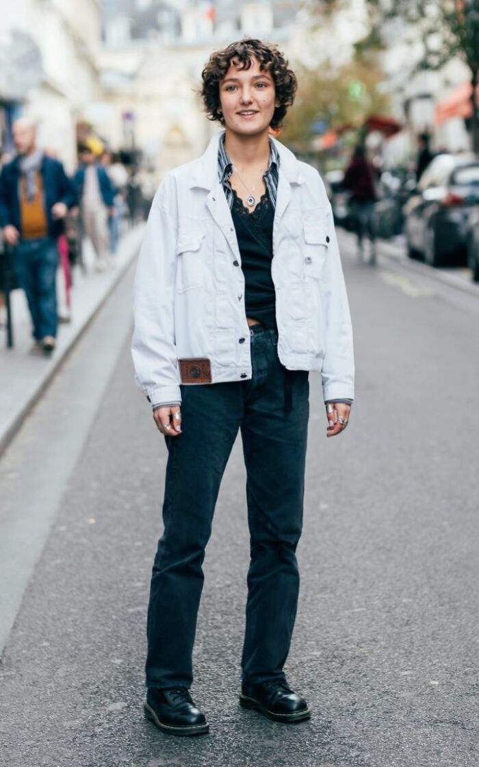Smiling stranger in a white jacket and black pants captured in a street portrait by a photographer.