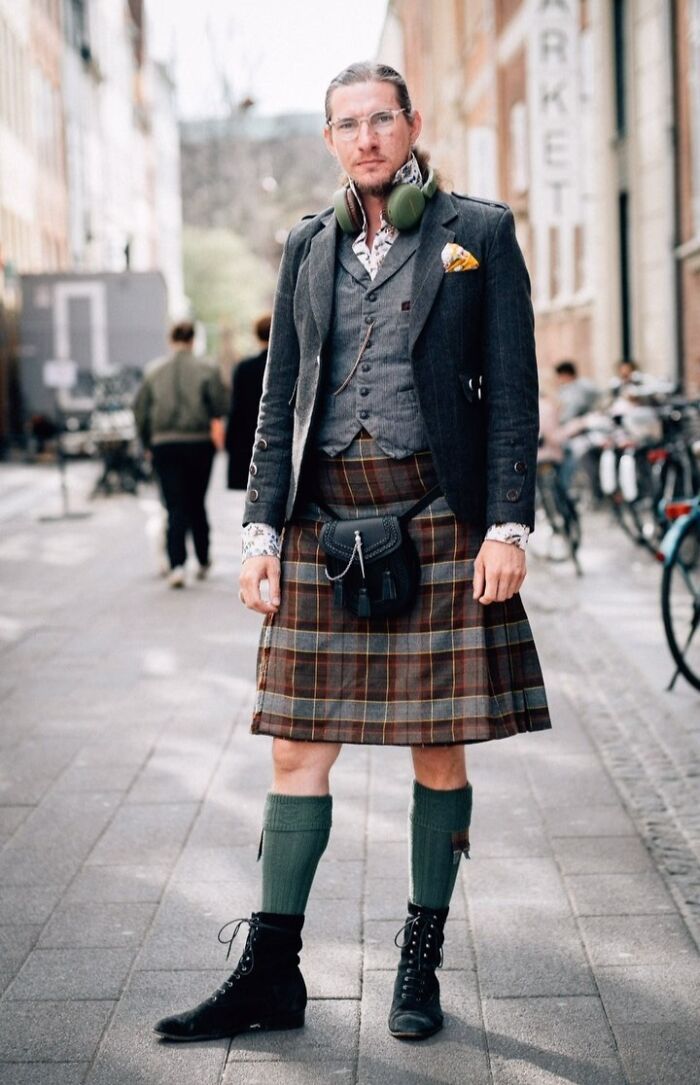 Portrait of a man in a stylish outfit with a kilt and glasses, embodying street portrait photography.