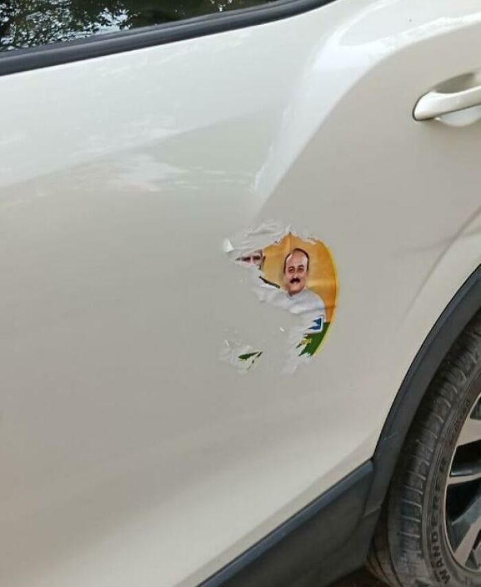 Damaged car with torn sticker of a person, showcasing entitled behavior.