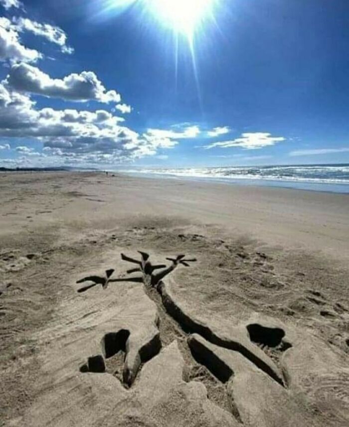 Beach sand art of a character from old cartoons under a bright sun, capturing nostalgia by the seaside.