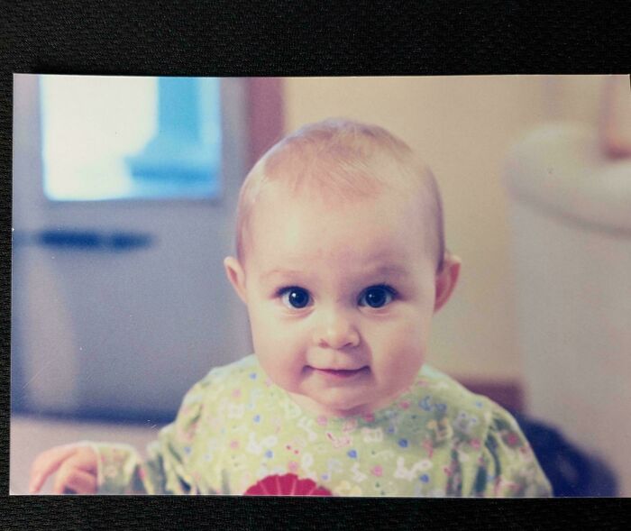 A smiling baby in a floral outfit, not related to book lovers or bookmarks.