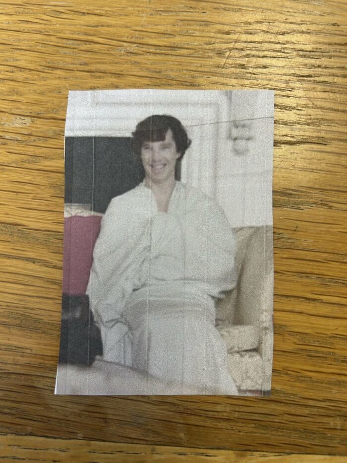 Unique bookmark featuring a smiling person printed on paper, placed on a wooden surface.