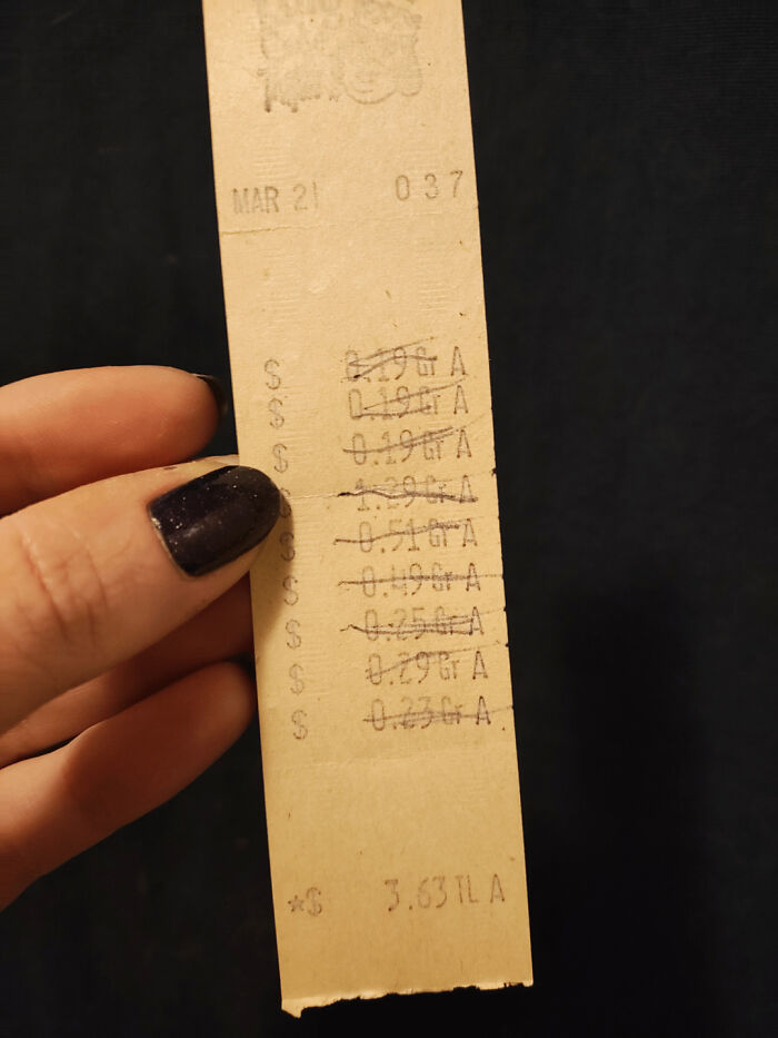Old receipt used as a bookmark, held by a person with dark nail polish.