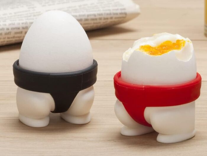 Egg holders with legs in black and red, from Peleg Design Shop, placed on a wooden table.