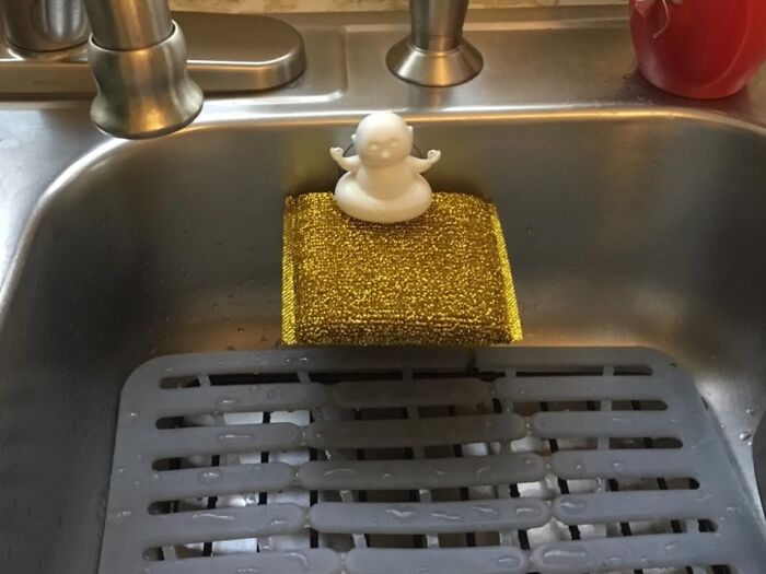 Duck-shaped soap holder on a golden sponge in a kitchen sink, by Peleg Design Shop.