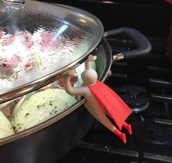Toy figure as a lid lifter on a cooking pot, showcasing Peleg Design Shop creativity.