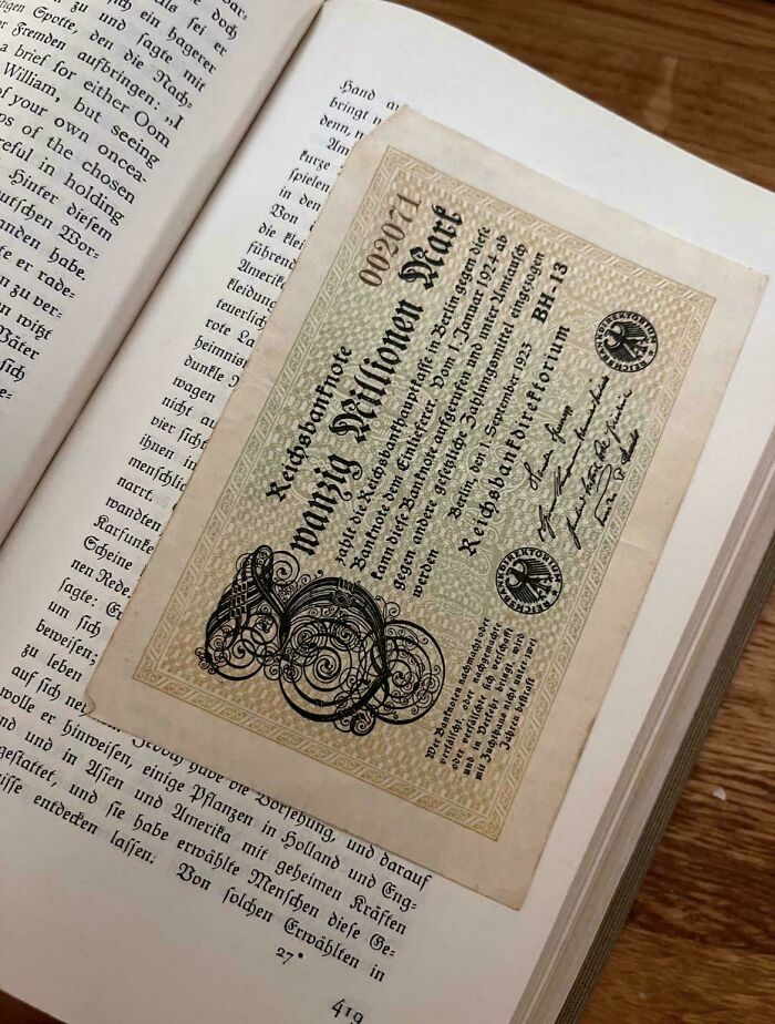 Book lovers using a vintage German banknote as a unique bookmark in an open book.