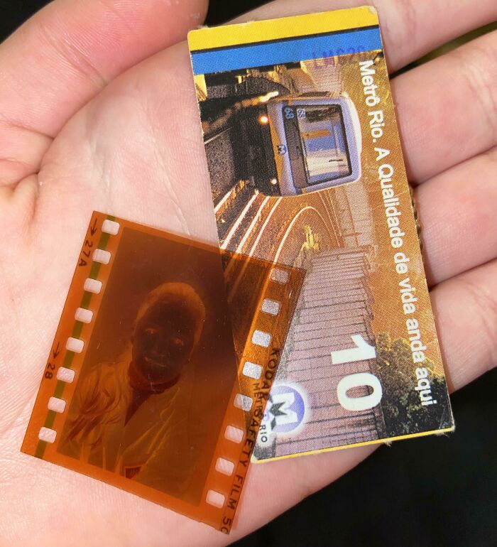 Hand holding unique bookmarks: a Metro Rio ticket and a film negative.