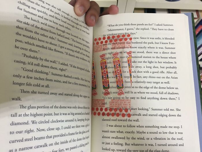 Book lovers using a colorful candy wrapper as a bookmark in an open book.
