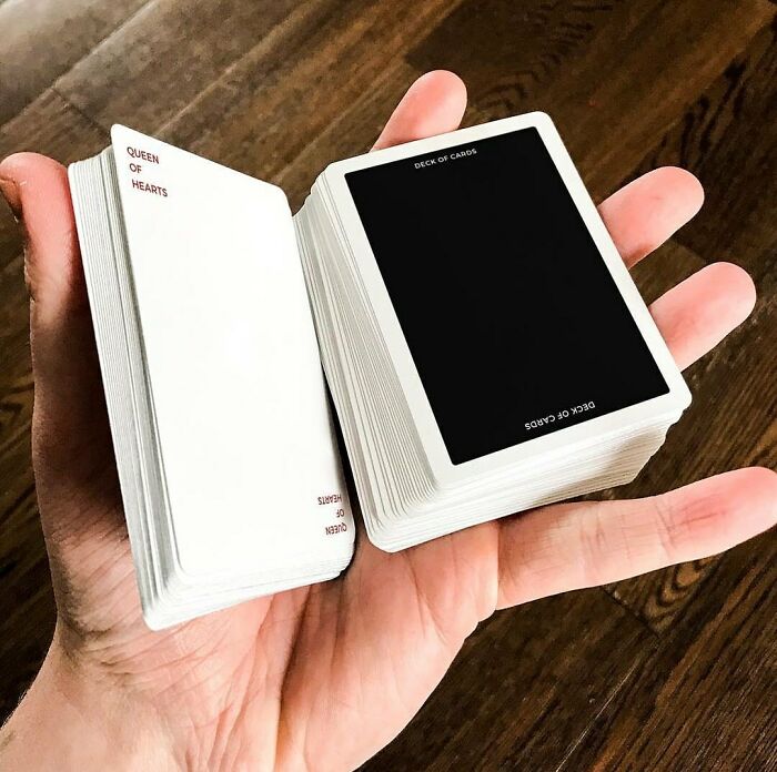 Hand holding misprinted playing cards with a design fail showing blank and black cards.