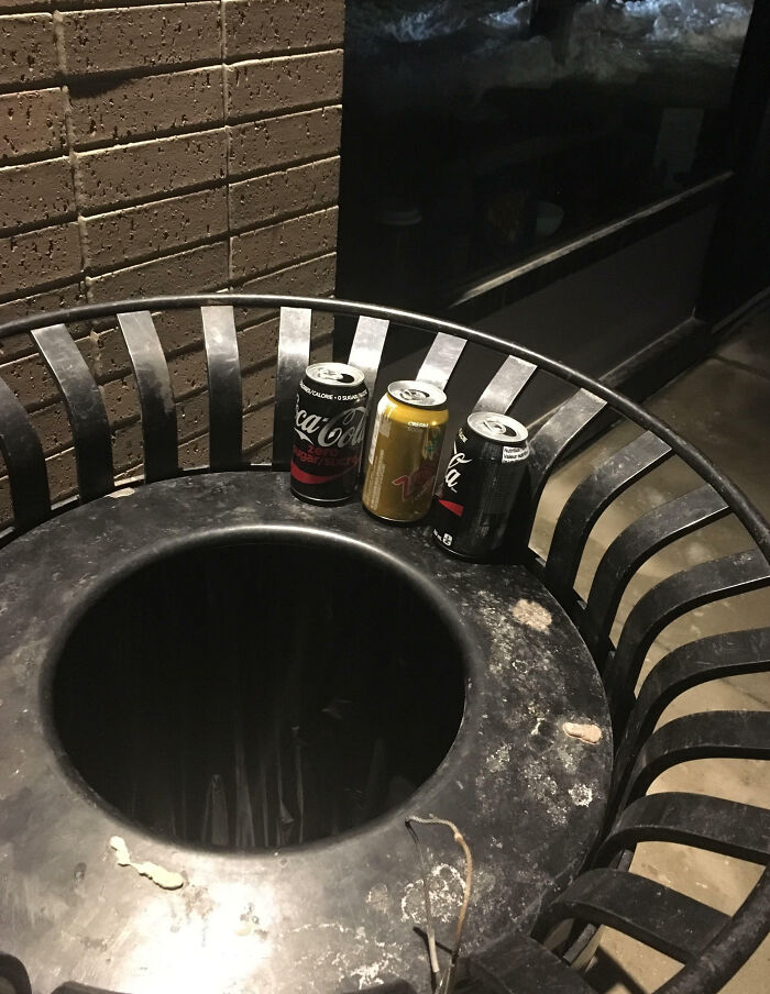 Three soda cans placed on the edge of a public trash can, illustrating things that only happen in Canada.