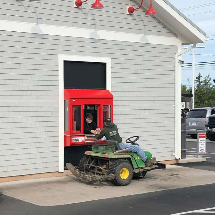 Person on a lawnmower in a drive-thru, exemplifying quirky Canadian behavior.