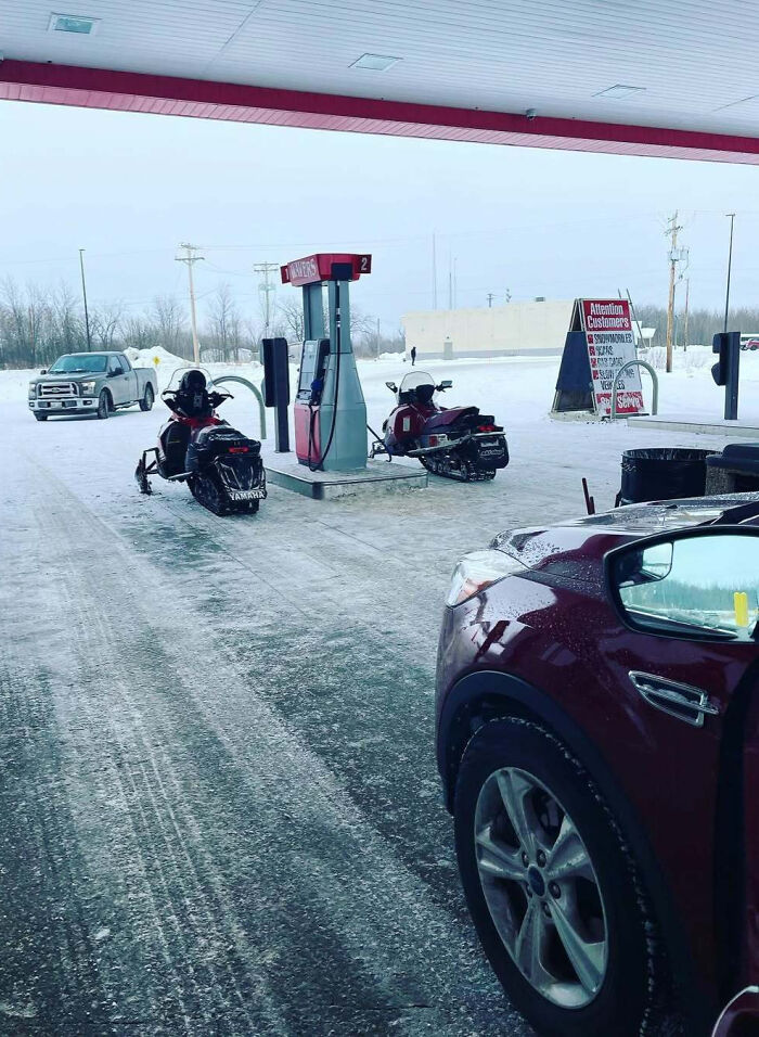 Snowmobiles refueling at a gas station during winter, showcasing just Canada things.