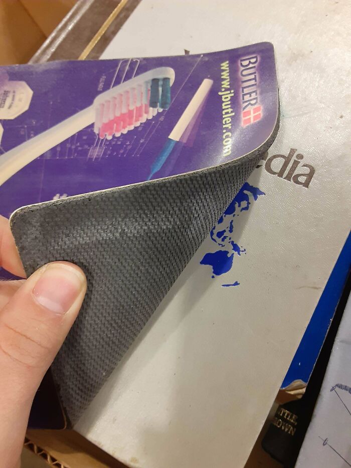 A creative bookmark made from a toothbrush advertisement, used by a book lover in a large hardcover book.